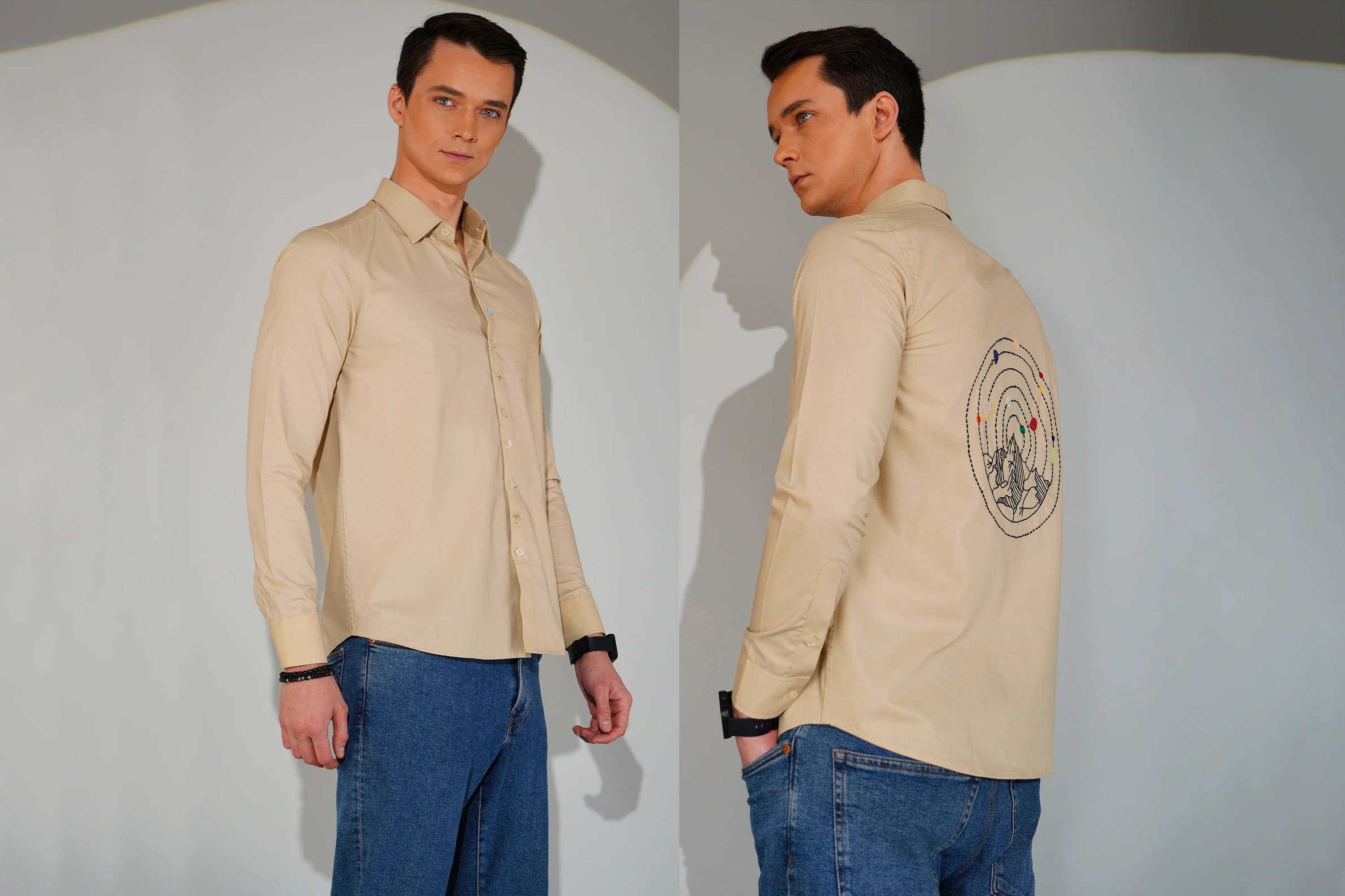 Man wearing a beige shirt with a logo on the sleeve against a plain background