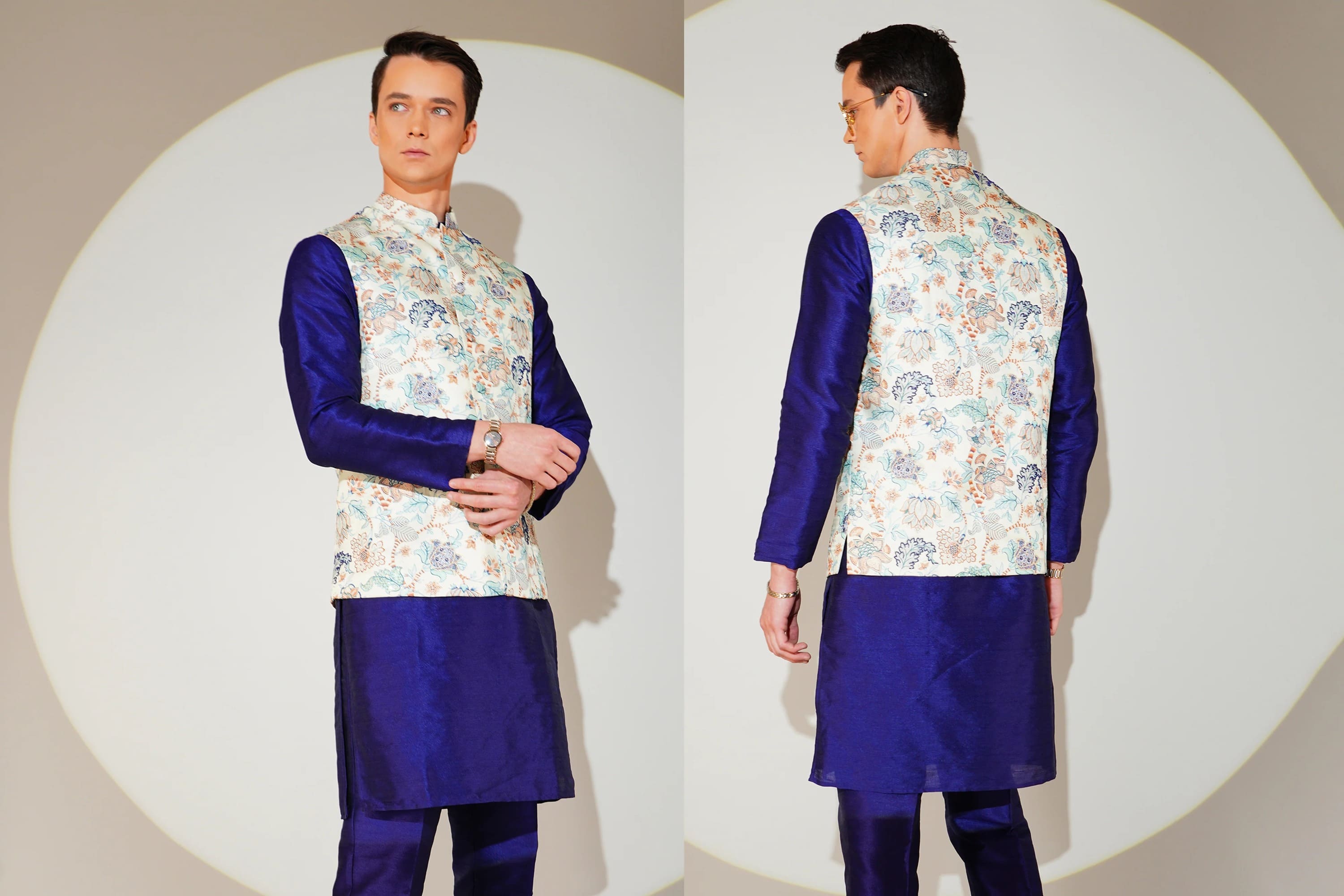 Man wearing a traditional outfit with a floral vest and blue kurta on a white background