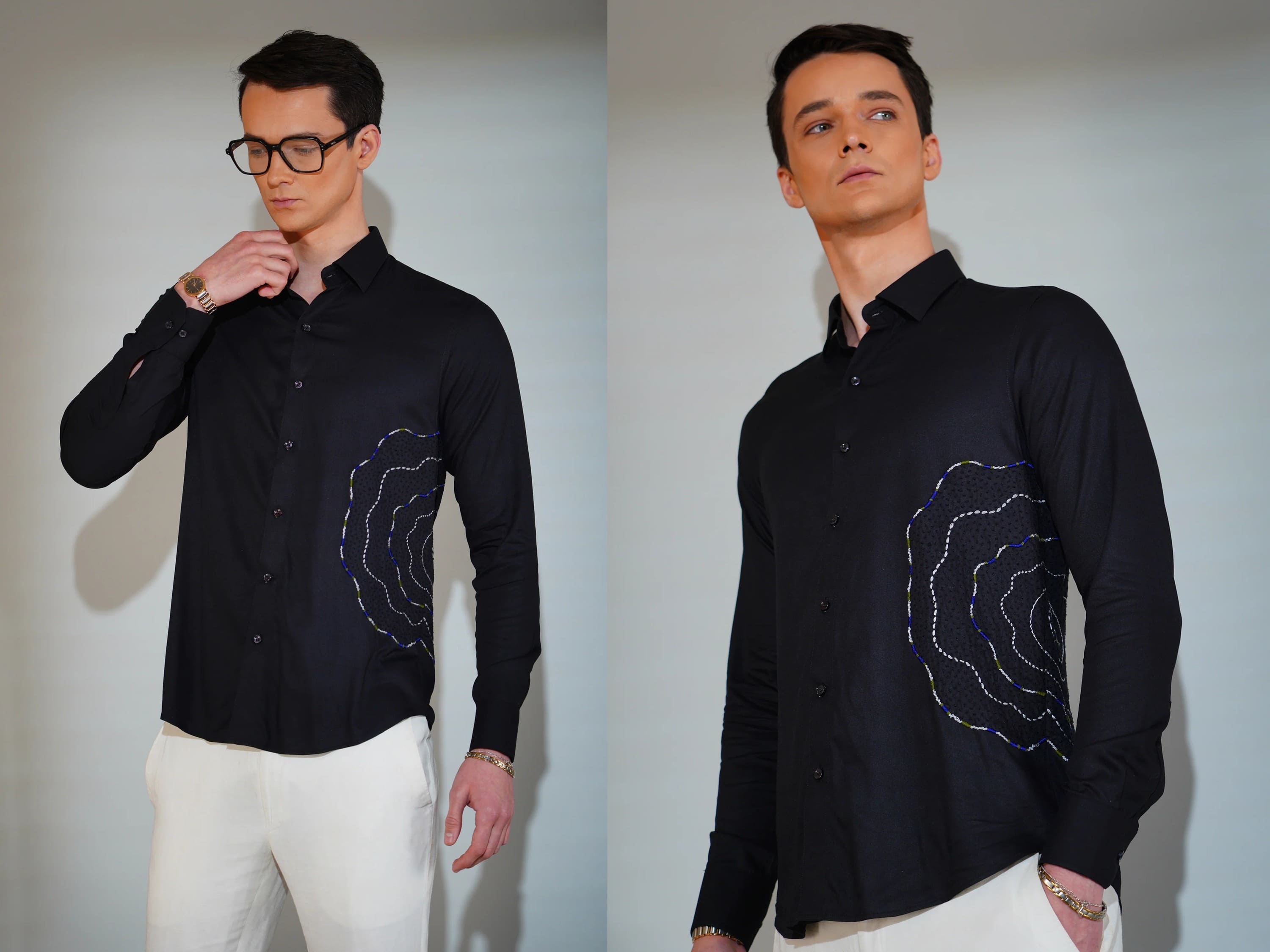 Man wearing a black shirt with a pattern, standing against a plain background.