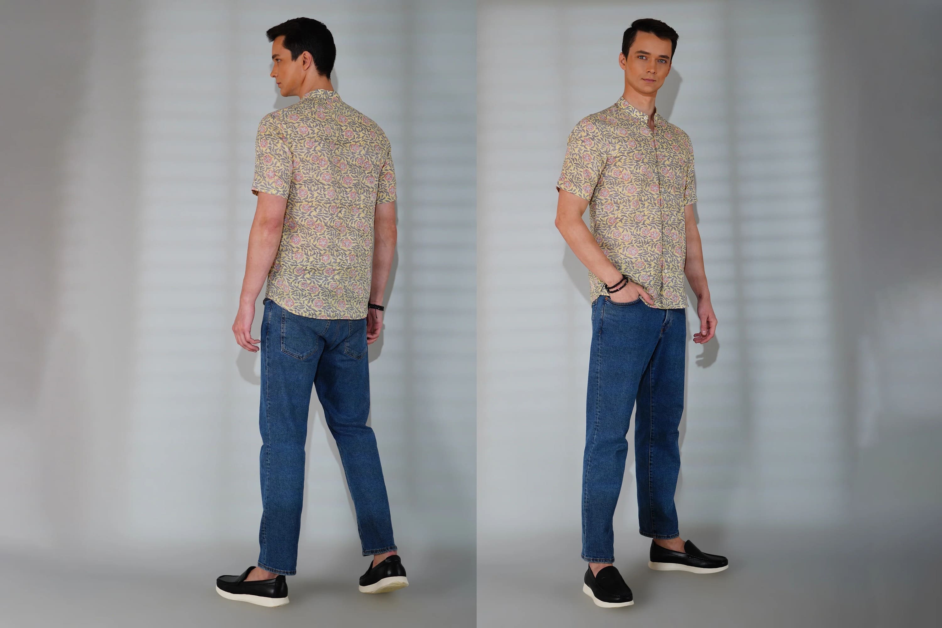 Man wearing a patterned shirt and blue jeans standing against a plain background